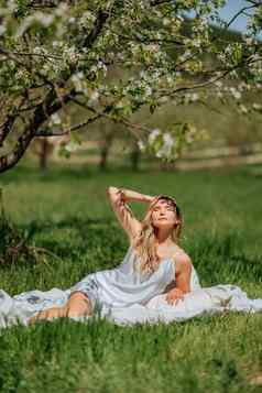 女人睡觉白色床上新鲜的春天草花园穿着蓝色的睡衣