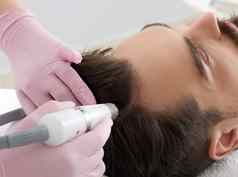 医生女皮肤科医生毛发学家使过程刺激头发增长头男人。