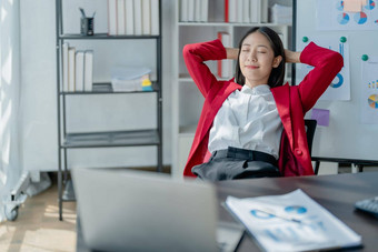 后视图年轻的女商人倾斜回来舒适的椅子坐着现代办公室成功的女人员工规划未来可视化思考项目策略