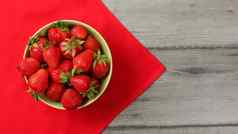 红色的成熟的草莓小碗桌布灰色的桌子上