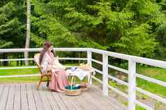 年轻的女人坐着阳台后院房子坐在扶手椅