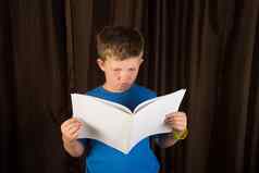年轻的男孩阅读空白书杂志