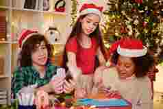 多民族集团有创意的孩子们使装饰房子圣诞节聚会，派对彩色的纸