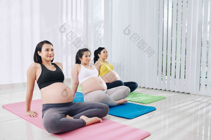 快乐漂亮的年轻的越南怀孕了女性坐着瑜伽垫培训类