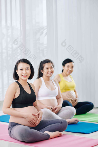 快乐微笑年轻的亚洲女性坐着瑜伽席<strong>体育类</strong>使心形状手