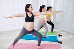 集团快乐的年轻的怀孕了女性参加瑜伽类战士构成
