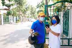 年轻的亚洲女人医疗面具接收订单离开提示快递应用程序智能手机