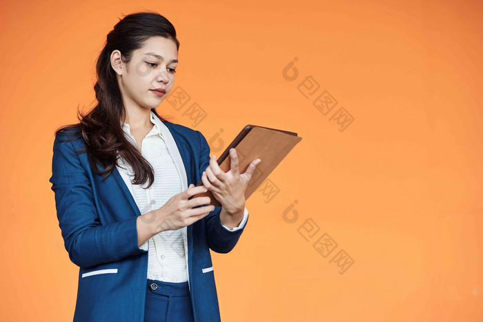 年轻的女企业家阅读文章平板电脑电脑孤立的橙色