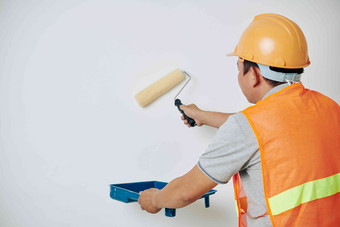 画家橙色背心需要戴安全帽的托盘抓多余的油漆绘画房子墙