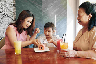 年轻的越南<strong>女人帮</strong>助女儿减少一块甜蜜的浆果蛋糕咖啡馆