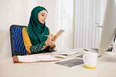 穆斯林女企业家坐着桌子上采取笔记规划师