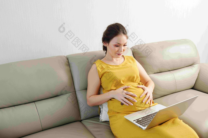 美丽的微笑年轻的亚洲女人触碰肚子看教育视频移动PC