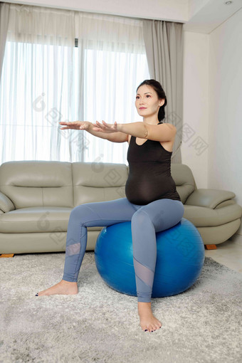 积极的年轻的越南怀孕了女人坐着健身球execises