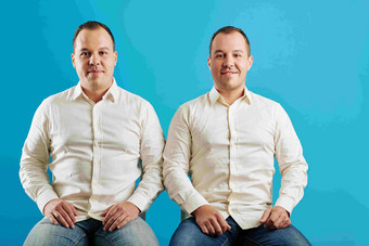 水平工作室肖像拍摄双胞胎兄弟坐着蓝色的墙背景相机