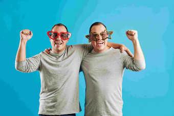 高加索人双胞胎兄弟穿有趣的眼镜准备好了普尔蒂相机明亮的蓝色的背景