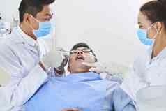 水平拍摄牙医牙科助理牙齿手术亚洲男人。
