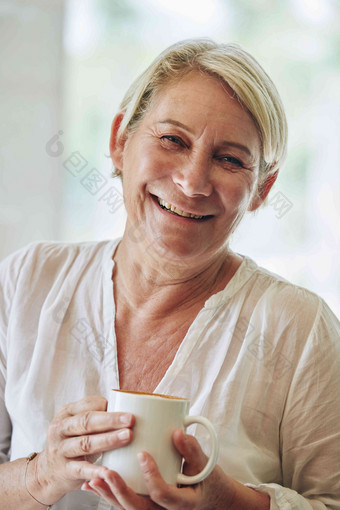 肖像微笑成熟的女人持有大杯子早....咖啡
