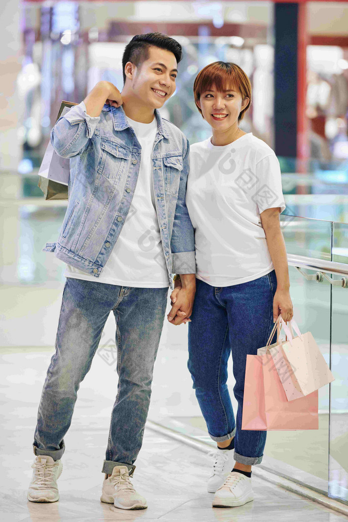 垂直完整的拍摄时尚的亚洲夫妇站现代购物购物中心持有袋