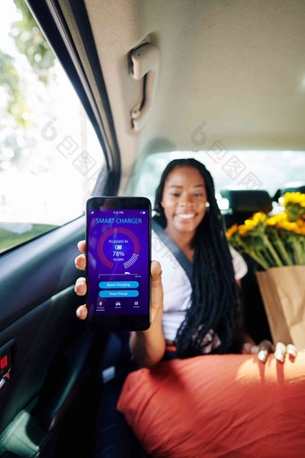 积极的年轻的女人坐着出租车后座显示<strong>智能</strong>手机聪明的充<strong>电器</strong>应用程序