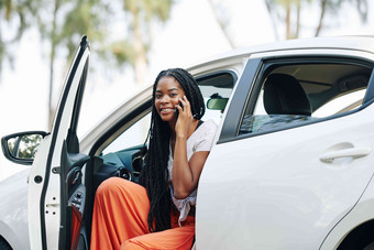 有吸引力的年轻的黑色的女人坐着车会说话的电话朋友的男朋友