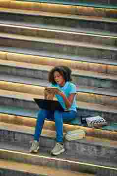 垂直拍摄集中青少年女孩搜索信息家庭作业项目书坐着楼梯在户外