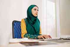 年轻的穆斯林女商人传统的衣服工作电脑办公室表格