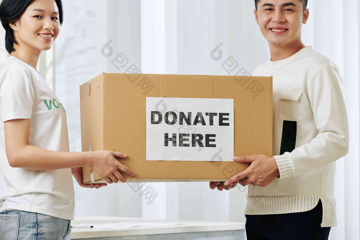 快乐的年轻的亚洲志愿者携带大纸板盒子捐赠衣服家庭项目