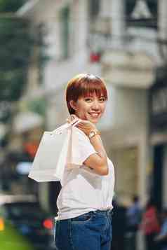 快乐年轻的亚洲女人休闲衣服站街纸袋手支出时间购物