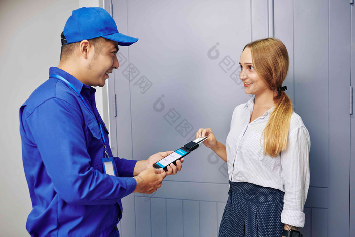 快乐的年轻的女人支付工作修理工信贷卡刷卡读者附加智能手机