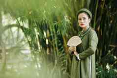 有吸引力的年轻的年轻的女人传统的越南服装走在户外雕刻木风扇