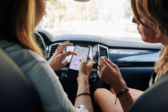年轻的女性坐着车地图智能手机屏幕讨论目的地点