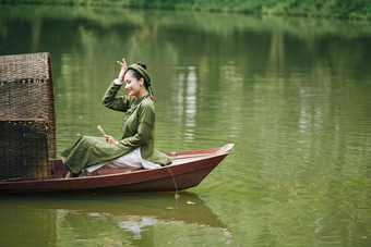 快乐的年轻的胎盘素女人传统的衣服坐着小船风扇手