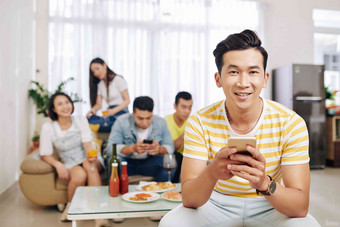 微笑越南年轻的男人。发短信相机朋友吃喝背景房子聚会，派对