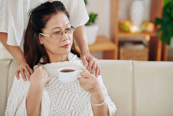 高级女人给杯茶温暖的毯子伤心沉思的朋友