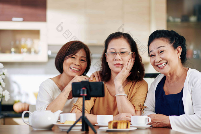 集团快乐上了年纪的女性会说话的自拍智能手机坐着厨房表格