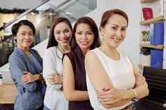 团队快乐自信成功的女商人站武器折叠微笑相机