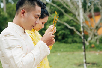 亚洲夫妇传统的服装祈祷香棒手