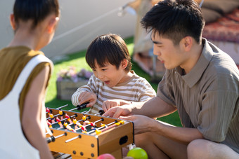 青年父亲和孩子在户外玩桌上足球桌子场景