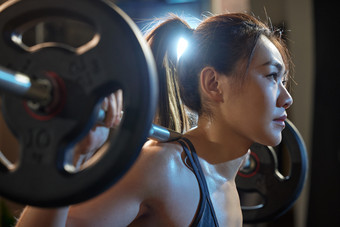 青年女人进行杠铃训练<strong>体育场馆</strong>