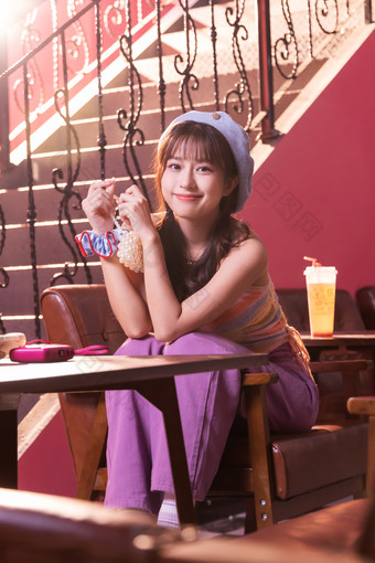 快乐的年轻女孩坐在餐厅里喝饮料街拍镜头