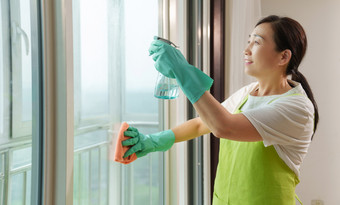 专业的家政服务人员擦拭门窗玻璃