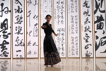 一位身穿民族服饰美女在书法前跳舞场景