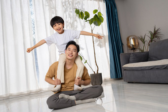 房间里一位亚洲男孩骑在父亲的肩膀上玩耍家影相