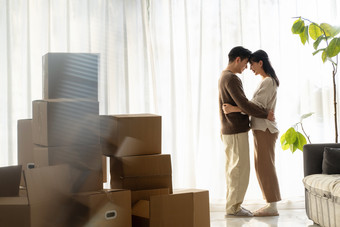 一对亚洲青年夫妇拥抱，房间里堆满着纸箱<strong>家装</strong>素材