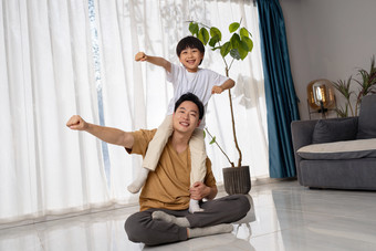 房间里一位亚洲男孩骑在父亲的肩膀上玩耍户内图片