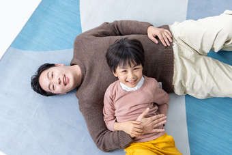 俯瞰房间里一位亚洲男孩和父亲躺在地板上玩耍摄影图