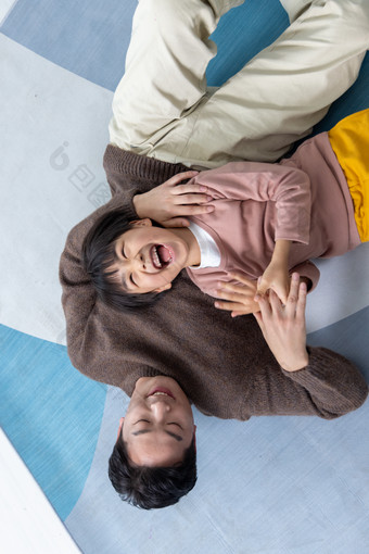幸福的男孩和父亲躺在地板上玩耍