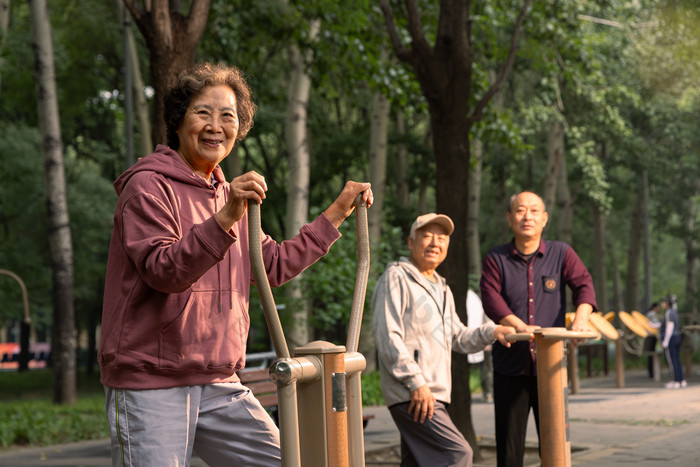 公园里使用锻炼器材锻炼身体的三位老年人老年女性