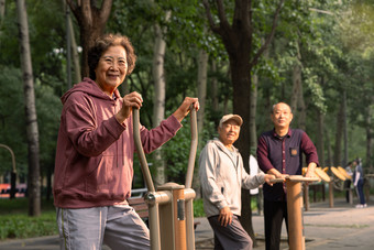 公园里使用锻炼器材锻炼身体的三位老年人老年女性