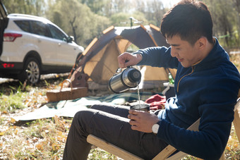 青年男人在户外露营坐着相片